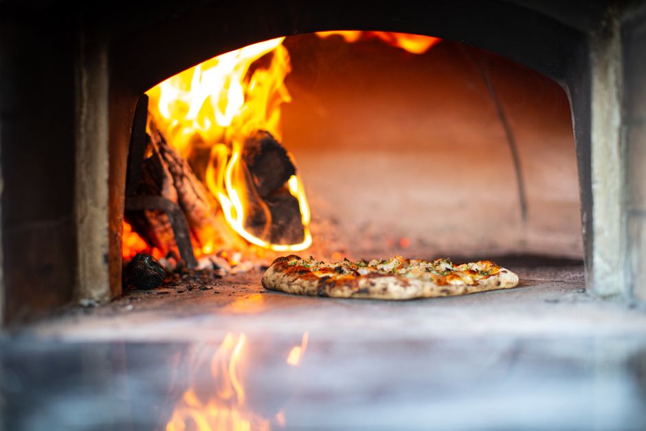 wood-fired pizza oven with flames and professional cooking setup
