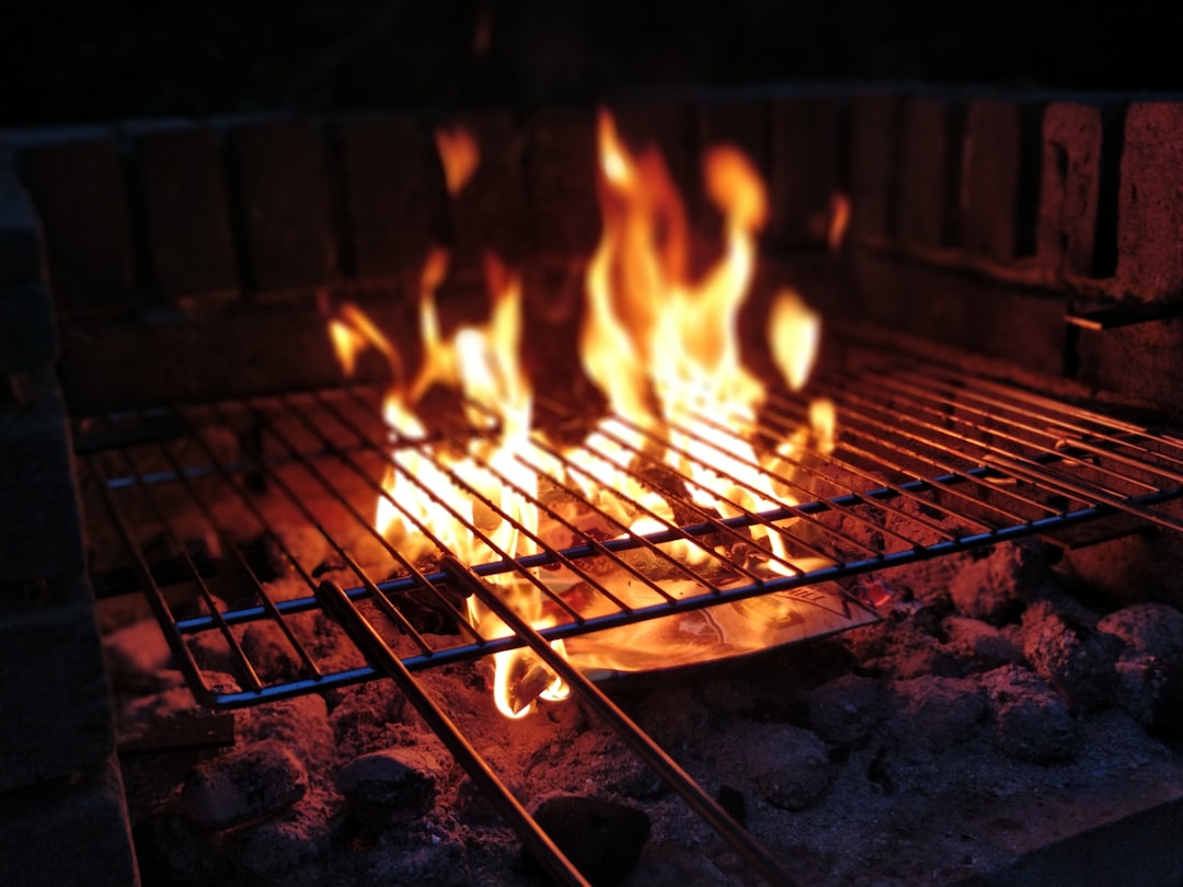 Food being grilled over open flames with smoke visible