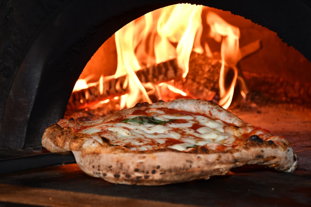 Wood-fired pizza oven with artisan pizza being prepared with visible flames